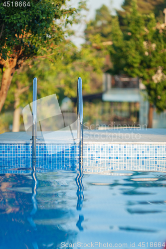 Image of An open swimming pool with a shiny railing and a sunny background