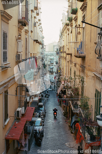 Image of Alleyway with motorbike driving among old houses in Naples, Italy