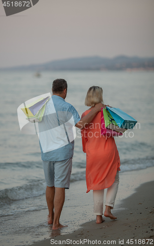 Image of A middle aged couple walking down the sea coast barefoot