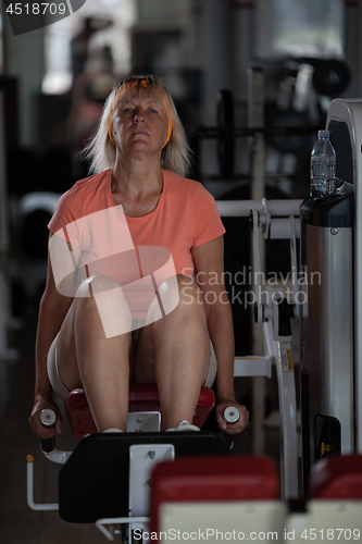 Image of A middle aged woman in a gym on one of the training machines