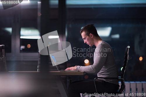 Image of man working on laptop in dark office