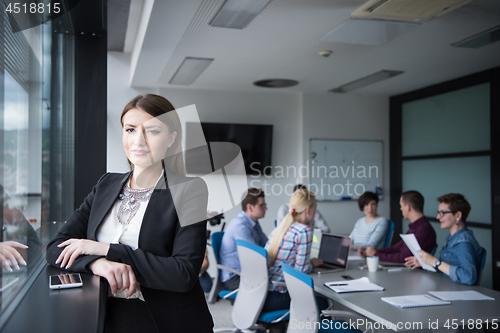 Image of Elegant Woman Using Mobile Phone by window in office building