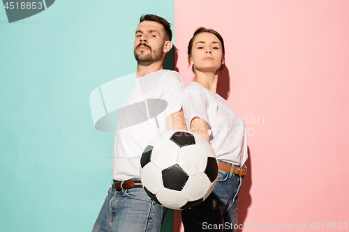 Image of The young proud and serious fans on blue and pink trendy colors.