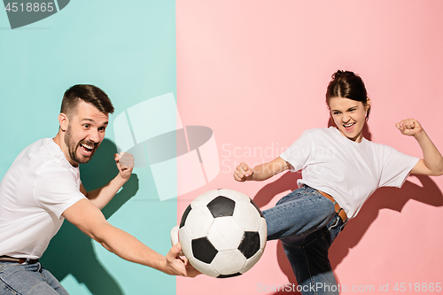 Image of The young football fans plaing with ball on blue and pink trendy colors.