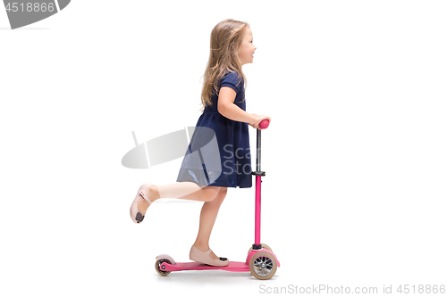 Image of Smiling cute toddler girl three years riding a scooter over white background