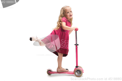 Image of Smiling cute toddler girl three years riding a scooter over white background
