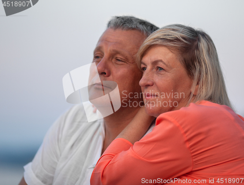 Image of A middle aged couple sitting close to each other and looking into the distance, smiling