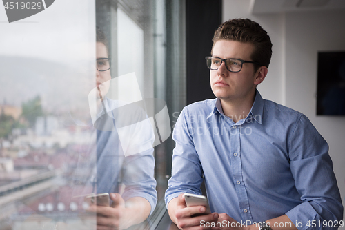 Image of Businessman Standing In A Modern Building Near The Window With P