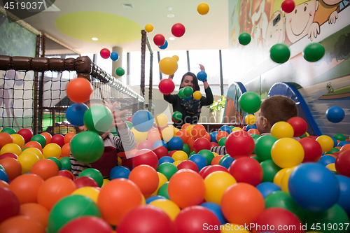 Image of Young mom with her kids in a children\'s playroom