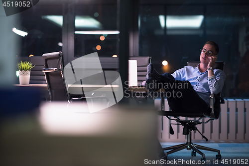 Image of businessman using mobile phone in dark office