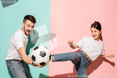 Image of The young football fans plaing with ball on blue and pink trendy colors.