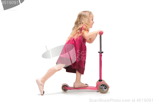 Image of Smiling cute toddler girl three years riding a scooter over white background