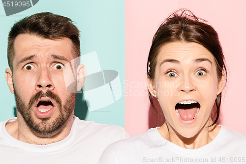 Image of Closeup portrait of young couple, man, woman. One being excited happy smiling, other serious, concerned, unhappy on pink and blue background. Emotion contrasts