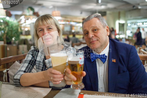 Image of A portrait of a smiling middle aged couple with glasses of beer