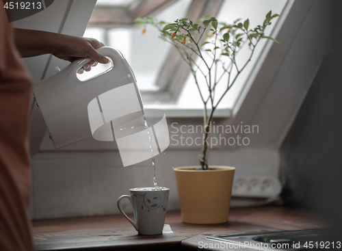 Image of Water flowing from the electric kettle to the cup