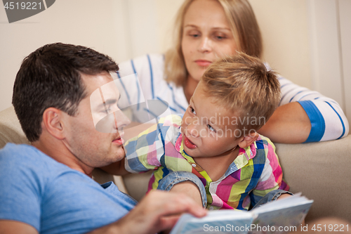 Image of Curious little boy with mum and dad. Reading book together