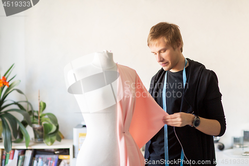 Image of fashion designer with dummy making dress at studio
