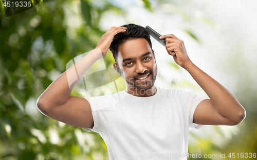 Image of indian man brushing hair over natural background