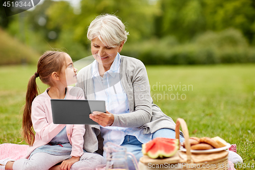 Image of grandmother and granddaughter with tablet at park