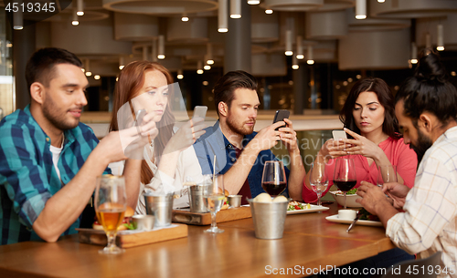 Image of friends with smartphones at restaurant