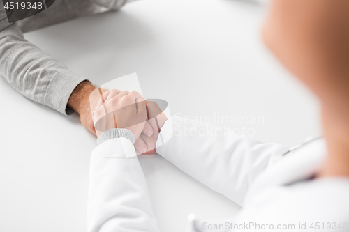 Image of close up of doctor holding senior patient hand