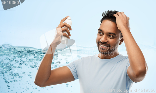 Image of smiling indian man applying hair spray over gray