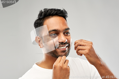 Image of indian man with dental floss cleaning teeth