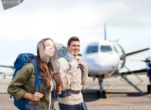 Image of couple of tourists with backpacks over plane