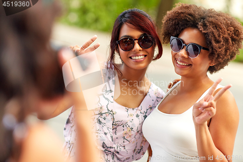 Image of woman photographing her friends in summer park