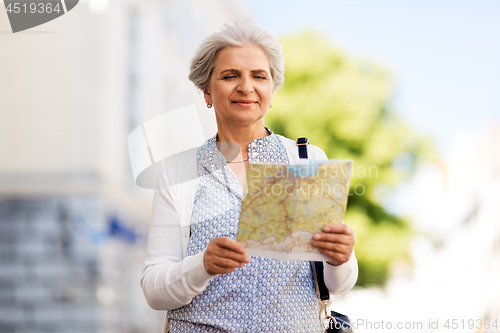 Image of senior woman or tourist with map on city street