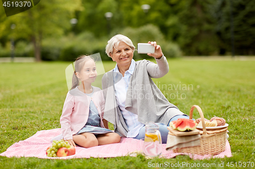 Image of grandmother and granddaughter take selfie at park