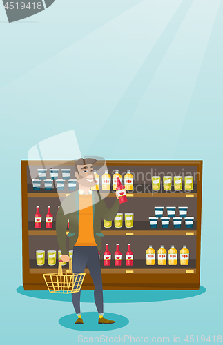 Image of Man holding shopping basket and bottle of sauce.