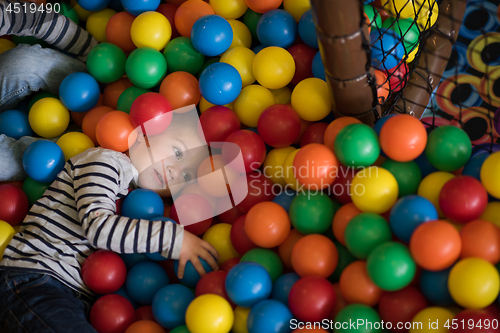 Image of boy having fun in hundreds of colorful plastic balls