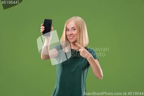 Image of Portrait of a confident casual girl showing blank screen mobile phone