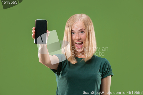 Image of Portrait of a confident casual girl showing blank screen mobile phone