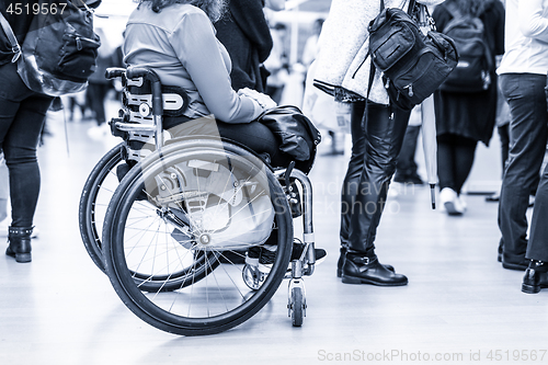 Image of Close up of unrecognizable hanicapped woman on a wheelchair queuing in line to perform everyday tasks.