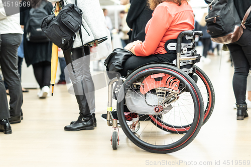 Image of Close up of unrecognizable hanicapped woman on a wheelchair queuing in line to perform everyday tasks.