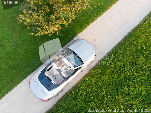 Image of Aerial view of successful man driving and enjoying his silver convertible luxury sports car on the open country side road