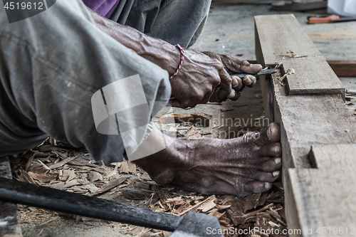 Image of Close up of warn hands of carpenter working in traditional manual carpentry shop in a third world country.