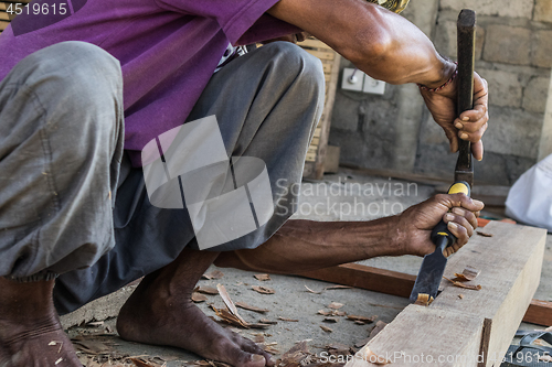 Image of Close up of warn hands of carpenter working in traditional manual carpentry shop in a third world country.