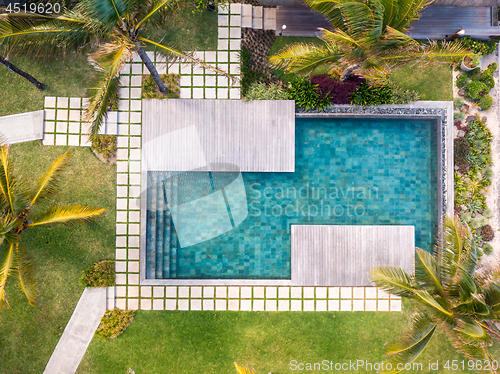 Image of Aerial view of luxury hotel resort with swimming pool with stair and wooden deck surrounded by palm trees.