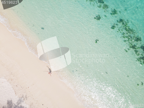 Image of Aerial shot of woman enjoying the picture perfect white tropica beach on Mauritius island.