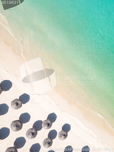 Image of Aerial view of amazing tropical white sandy beach with palm leaves umbrellas and turquoise sea.