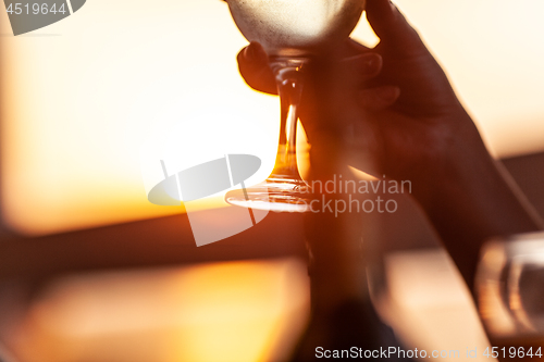 Image of Wineglass in female hand against the sunset