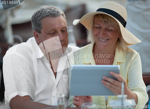 Image of Cheerful mature couple with touch pad outdoor