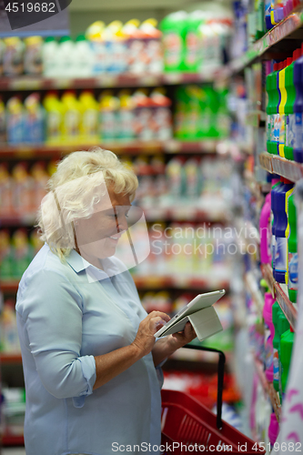 Image of A middle aged woman with a tablet in a household section of a supermarket