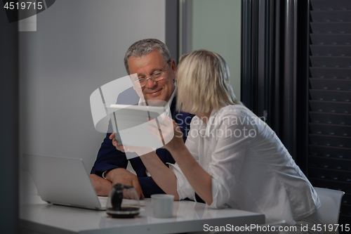 Image of A middle aged couple at the table with their devices