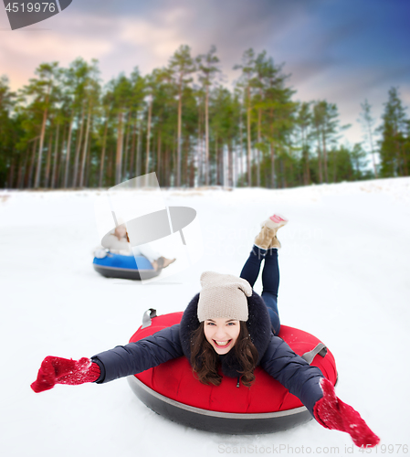 Image of happy teenage girl sliding down hill on snow tube