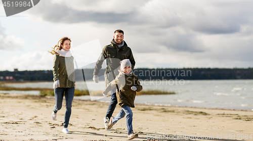 Image of happy family running along autumn beach