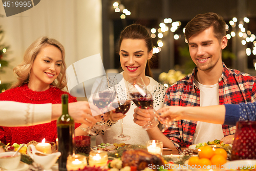 Image of happy friends drinking red wine at christmas party